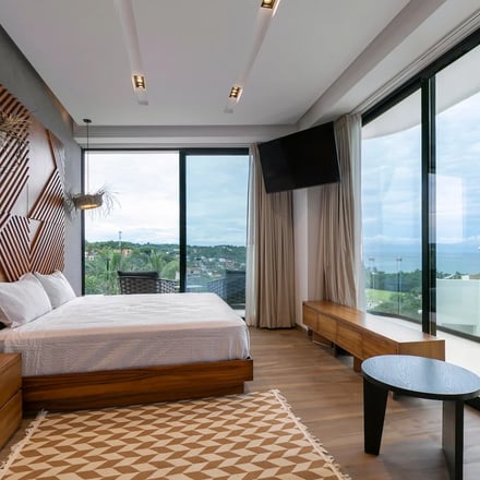Bedroom with walnut headboard and panoramic ocean and town views
