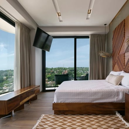 Bright bedroom with floor-to-ceiling windows and jungle views