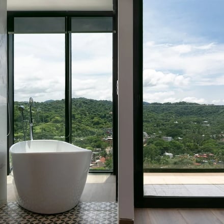 Freestanding bathtub with floor-to-ceiling jungle views