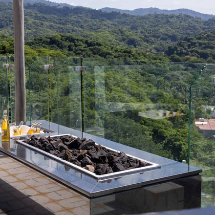 Rooftop fire pit with glass railing and jungle hillside backdrop