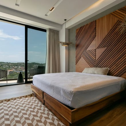 Bedroom with walnut headboard and ocean view balcony