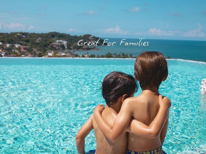 Two children at the rooftop infinity pool overlooking the ocean at El Cielo